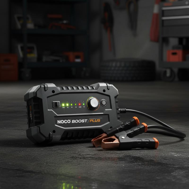 Booster de batterie NOCO Boost Plus GB40 posé sur un sol de garage sombre et texturé, éclairage contrasté mettant en valeur les boutons et le boîtier robuste